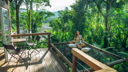 a woman sitting on a deck with a view at La Chagra VIP - Cabaña & Glamping en Villavicencio in Villavicencio