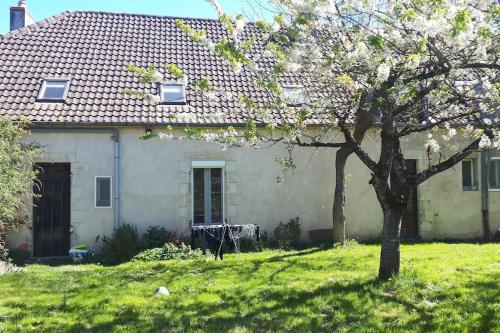 une maison blanche avec un arbre dans la cour dans l'établissement Gîte à la ferme, avec animaux, fromages et nature, à Neuville-lès-Decize