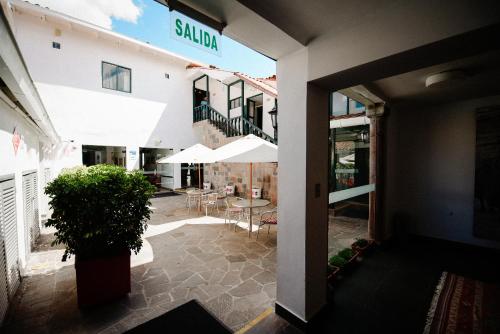 a patio with tables and umbrellas outside of a building at Hotel Raymi in Cusco