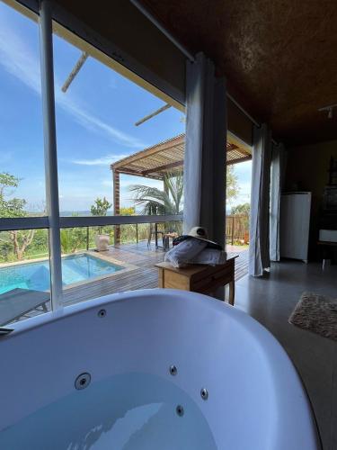 a bath tub in a bathroom with a view of a pool at OKA VIVAH - Chalé Oka do Sol in Jaboticatubas