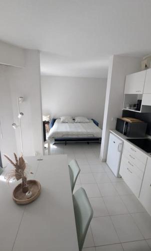 - une cuisine blanche avec une table et un lit dans l'établissement T2 ouvert à 5 min des plages, au calme, avec balcon et garage, à Menton