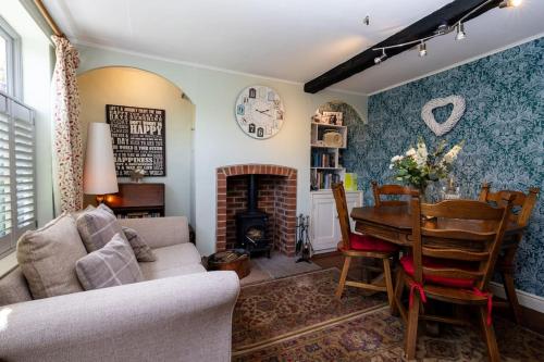 a living room with a table and a fireplace at Clematis Cottage Tealby LN8 3XU in Tealby