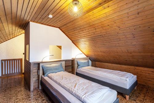 two beds in a room with a wooden ceiling at Azalea in Olsberg
