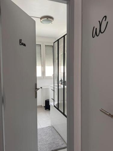 d'une salle de bains avec une porte s'ouvrant sur une salle de bains pourvue d'un lavabo. dans l'établissement Appart premium à 5 min de l aeroport Orly, à Athis-Mons