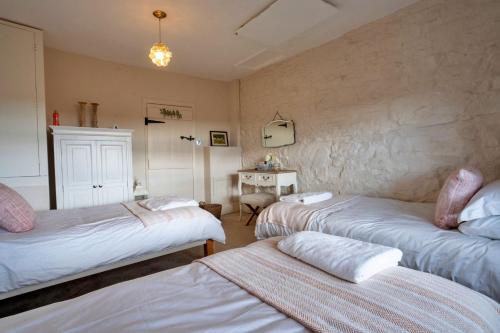 a room with three beds and a table in it at Finest Retreats - Blackclough Farmhouse at Blackclough Farm in Buxton