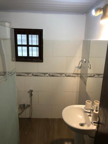 ein weißes Badezimmer mit Waschbecken und Fenster in der Unterkunft Chuy Aparts 1 in Chuy