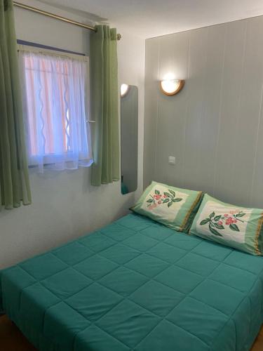 - une chambre avec un lit vert et une fenêtre dans l'établissement Bel appartement à 5 mn de la mer et du centre-ville - Résidence Les Gémeaux, à Saint-Aygulf