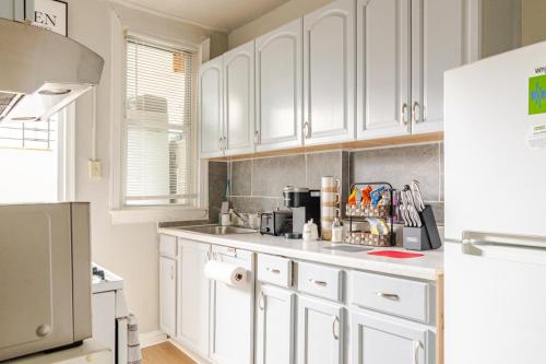 a white kitchen with white cabinets and a refrigerator at Stylish & Family Friendly 2BR at Downtown Washington DC in Washington, D.C.