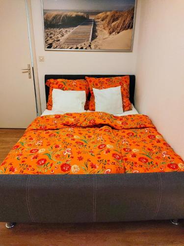 - un lit avec une couverture orange et des oreillers dans l'établissement Appartement T3 proche de Bâle, à Saint-Louis