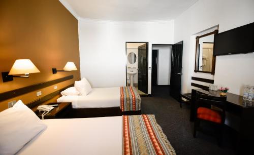 a hotel room with two beds and a mirror at Hotel Raymi in Cusco