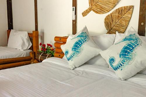 a bed with blue and white pillows on it at Marazao Beach Hotel & Spa in Tierra Bomba