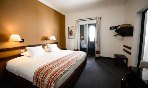 a hotel room with a large bed and a window at Hotel Raymi in Cusco