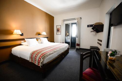 a hotel room with a bed and a television at Hotel Raymi in Cusco