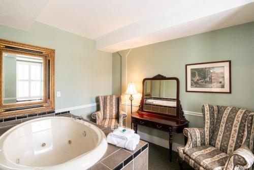 a bathroom with a tub and two chairs and a mirror at Lake Lure Inn and Spa in Lake Lure