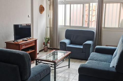 a living room with two blue chairs and a tv at Sunset Plateau in Praia