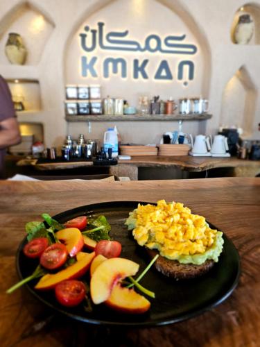 a plate of food with eggs and fruit on a table at كمكان kmkan in Bahlāʼ