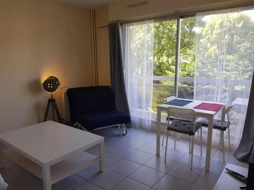 une pièce avec une table, une chaise et une fenêtre dans l'établissement Appartement moderne aux Pavillons-sous-Bois - 24 m² + Terrasse, à Les Pavillons-sous-Bois