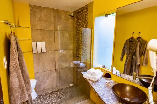 a yellow bathroom with a sink and a shower at Villa Côté Sud Pousada De Charme in São Miguel dos Milagres