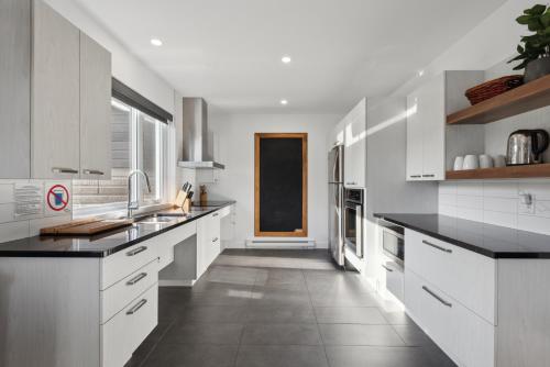 a kitchen with white cabinets and black counter tops at Les Chalets Baie Cascouia in Lac Kénogami