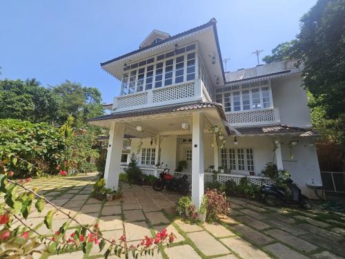 a large white house with a porch at Padikkal Bungalow in Vayittiri