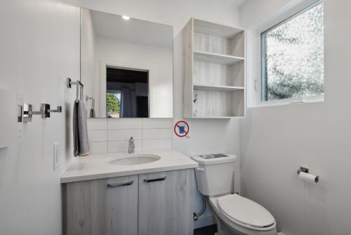 a white bathroom with a toilet and a sink at Les Chalets Baie Cascouia in Lac Kénogami