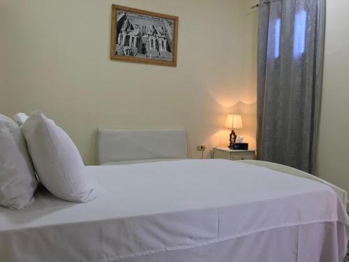 a bedroom with a white bed and a chair at Sakkara pyramid inn hotel in Cairo