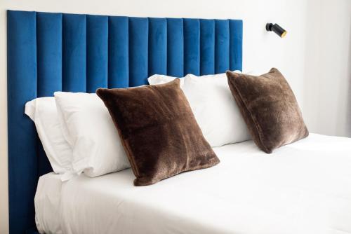 a bed with white pillows and a blue headboard at The Rubens Collection in Rome