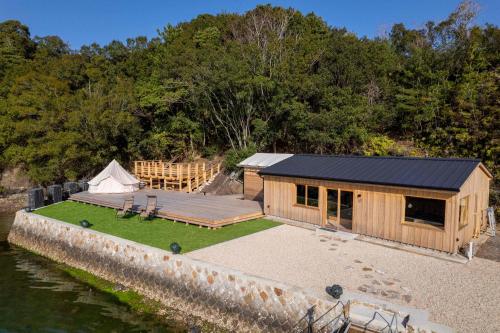 a wooden cabin next to the water with a tent at 船で行く 1日1組限定の絶景宿 うみらぼ in Shima