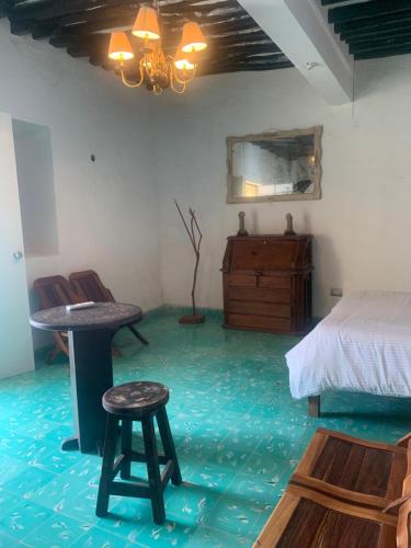 a bedroom with a bed and a table and two stools at casa pich balam in Valladolid