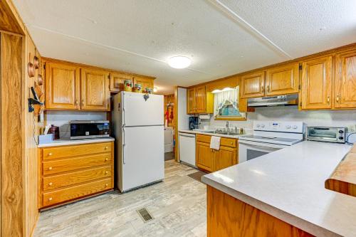 a kitchen with wooden cabinets and a white refrigerator at Creek Access and Spacious Yard Quiet Sylva Home! in Sylva