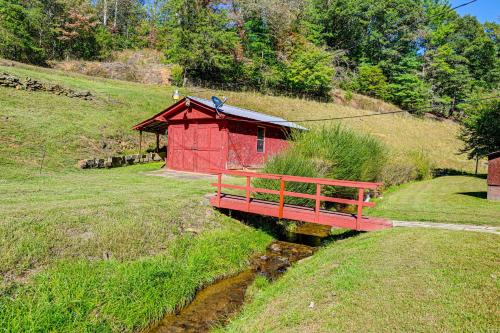 a redshed sitting on a hill next to a river at Creek Access and Spacious Yard Quiet Sylva Home! in Sylva