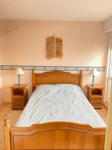 - une chambre avec un lit en bois et 2 tables de chevet dans l'établissement Apt T2 climatisé à 2 min plage du mole avec balcon et piscine, au Cap d'Agde