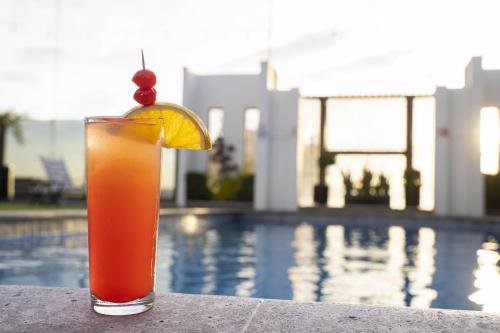 a drink sitting on a ledge next to a pool at Hotel Real Plaza in San Luis Potosí