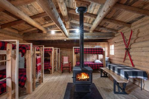 a room with a fireplace in a log cabin at ÖBois Charlevoix - Le Refuge in Saint-Siméon