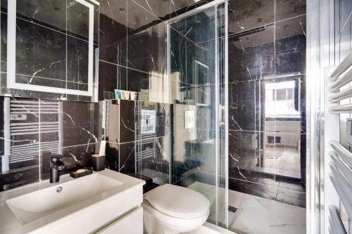 La salle de bains est pourvue de carrelage noir, de toilettes et d'un lavabo. dans l'établissement Bluestay 57 - Charmant appartement à Paris, à Paris