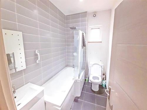 a bathroom with a toilet and a tub and a sink at London City Apartment in Eltham