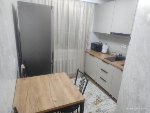 a kitchen with a wooden table and a refrigerator at 3-х комнатная квартира Аэропорт in Turksib