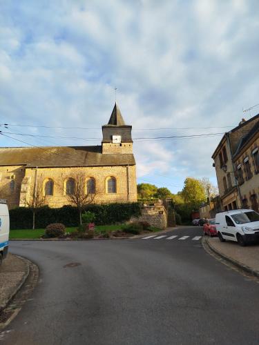 un vieux bâtiment avec une tour d'horloge dans une rue dans l'établissement l'èrmitage, à Floing
