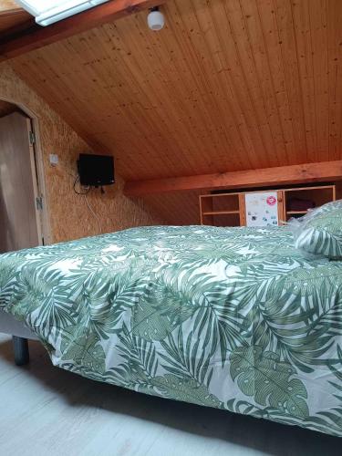 - un lit avec une couette verte et blanche dans l'établissement La Cachotière du Lac, à Giffaumont