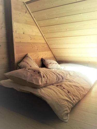 un lit dans une chambre avec un mur en bois dans l'établissement Chalet au cœur du massif des Bauges, à La Féclaz