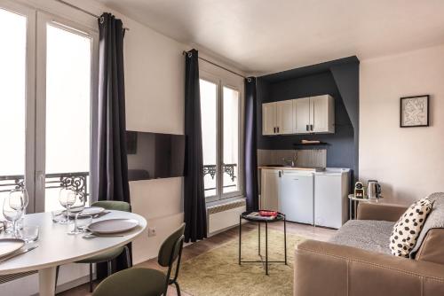 Il comprend un petit salon avec une table et une cuisine. dans l'établissement Charming Apartment - Atelier Lumières - 4 guests, à Paris