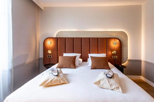 a bedroom with a large white bed with two pillows at Mercure Angoulême Hôtel de France in Angoulême