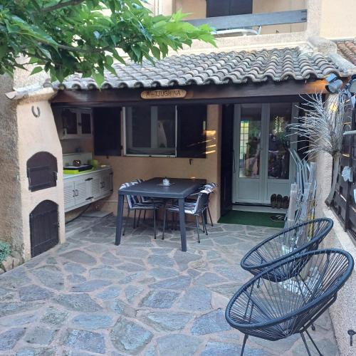 un patio avec une table et des chaises et une cuisine dans l'établissement A-Tjughina, à San Ciprianu