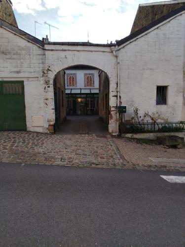 un ancien bâtiment en briques blanches avec une arche dans l'établissement l'èrmitage, à Floing