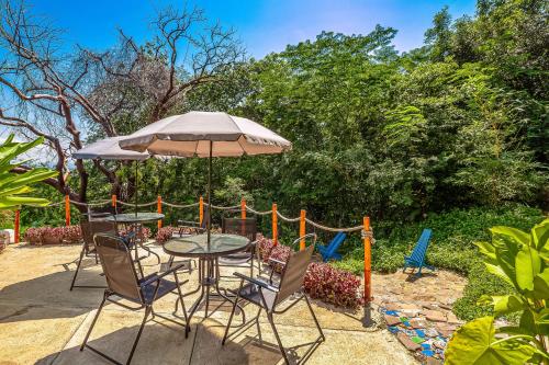 a patio with a table and chairs and an umbrella at Villa Heliconia in Barra de Navidad