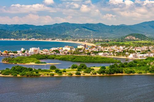an island in the water with a city at Villa Heliconia in Barra de Navidad