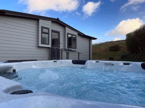 a hot tub in front of a house at Cosy Clos Y Hendy Lodge in Penbryn