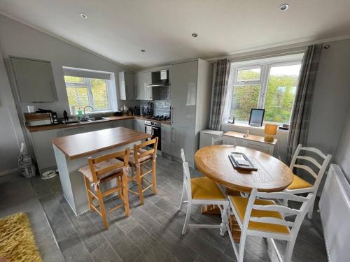a kitchen and dining room with a table and chairs at Cosy Clos Y Hendy Lodge in Penbryn