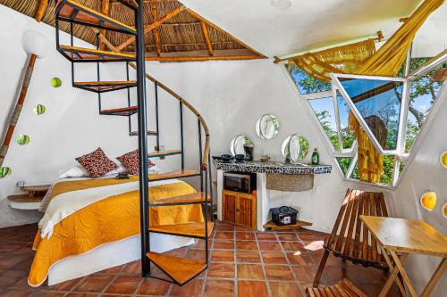 a bedroom with a bed and a spiral staircase at Villa Heliconia in Barra de Navidad