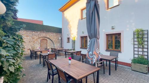 a patio with wooden tables and chairs and an umbrella at PENZION BLANKA - Znojmo in Znojmo